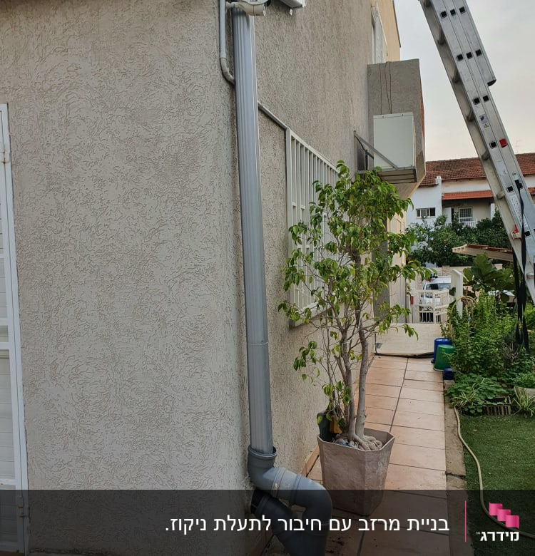 צינור ניקוז אפור מחובר לקיר חיצוני של בניין